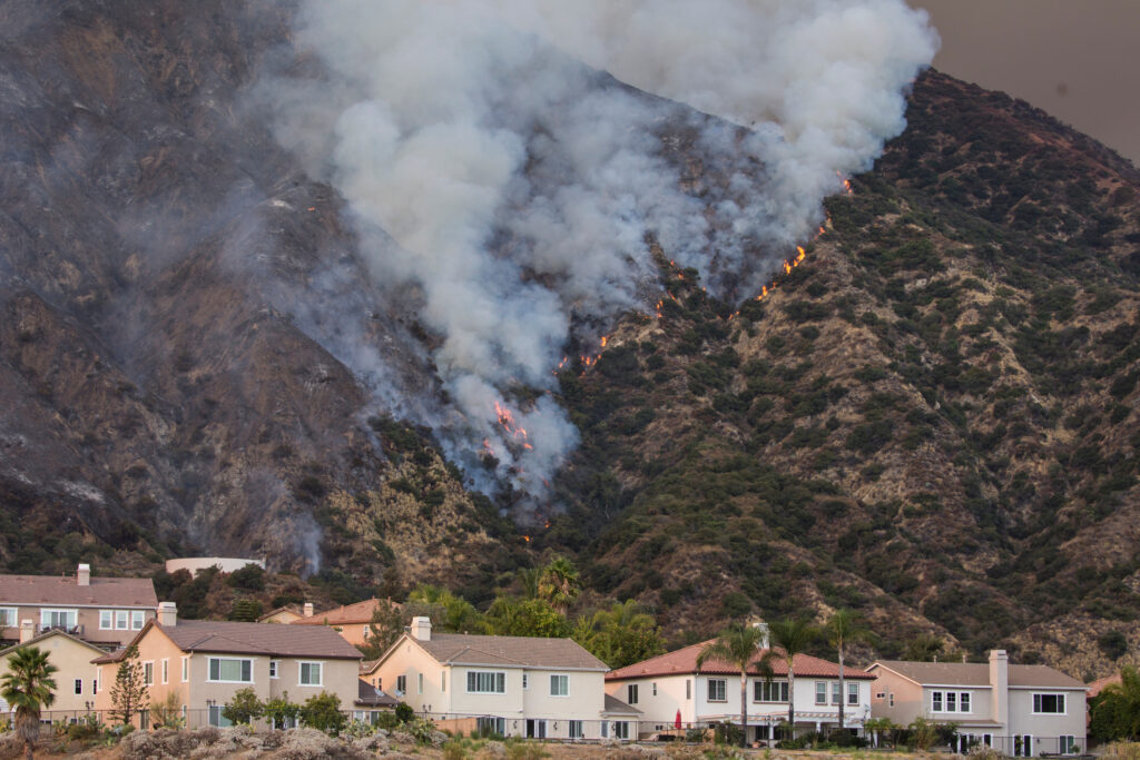A wildfire burns the hillside behind homes on Wednesday, Aug. 12, 2020, Azusa, California.