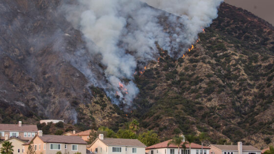 A wildfire burns the hillside behind homes on Wednesday, Aug. 12, 2020, Azusa, California.